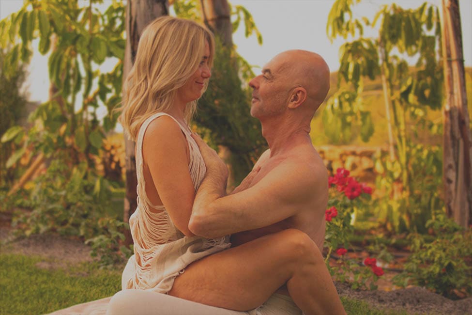 Mónica and Peter, founders of Connective Tantra School, sitting face to face in a mindful outdoor practice at sunset