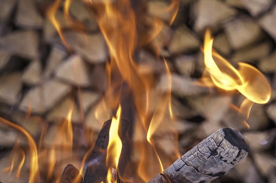 FUEGO: ejercicios de respiración tántrica para cada elemento por Connective Tantra School Primer plano de llamas danzantes sobre troncos ardiendo, representando la transformación, la pasión y el elemento Fuego en los ejercicios de respiración tántrica.