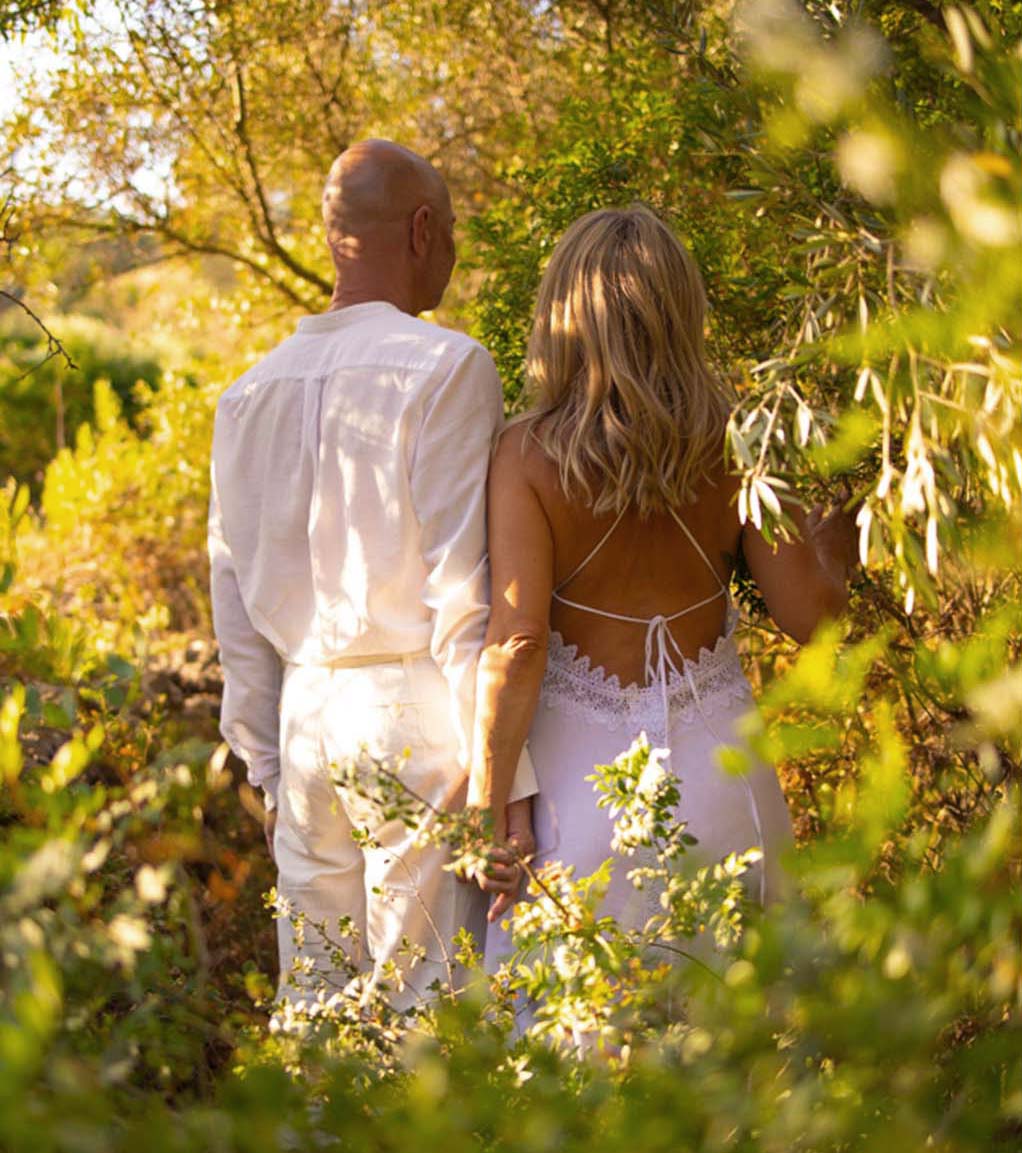 Pareja caminando lado a lado después de un viaje de sanación Mónica y Peter de Connective Tantra School sentados en la naturaleza, frente con frente con las manos en oración, practicando la comunicación y la presencia tántrica.